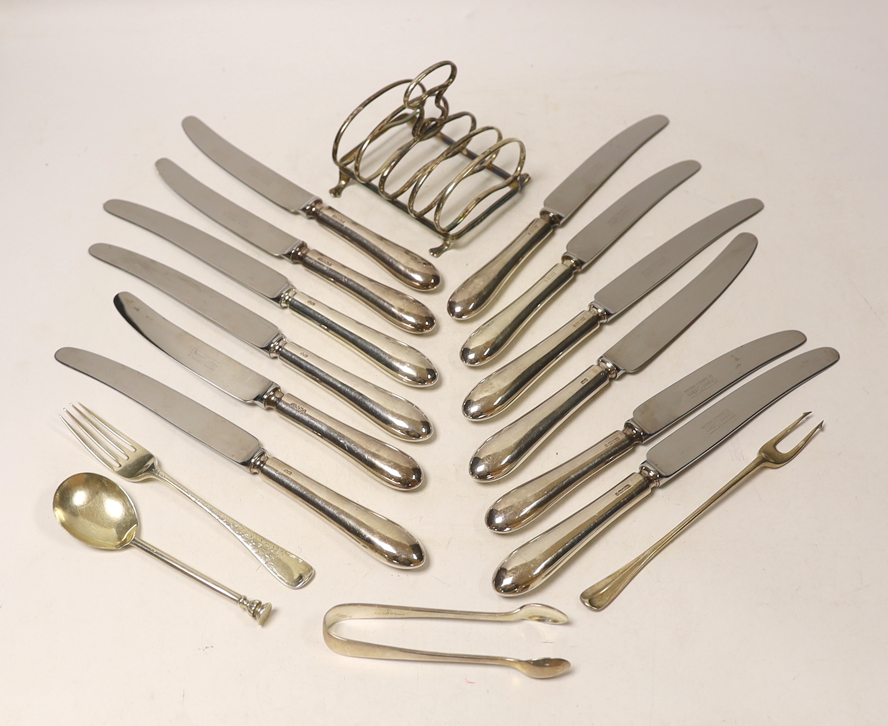 A set of six modern silver handled table knives and dessert knives, United Cutlers, Sheffield, 1997/8, a small silver five bar toast rack, two silver forks, a silver spoon and a pair of silver plated sugar tongs.